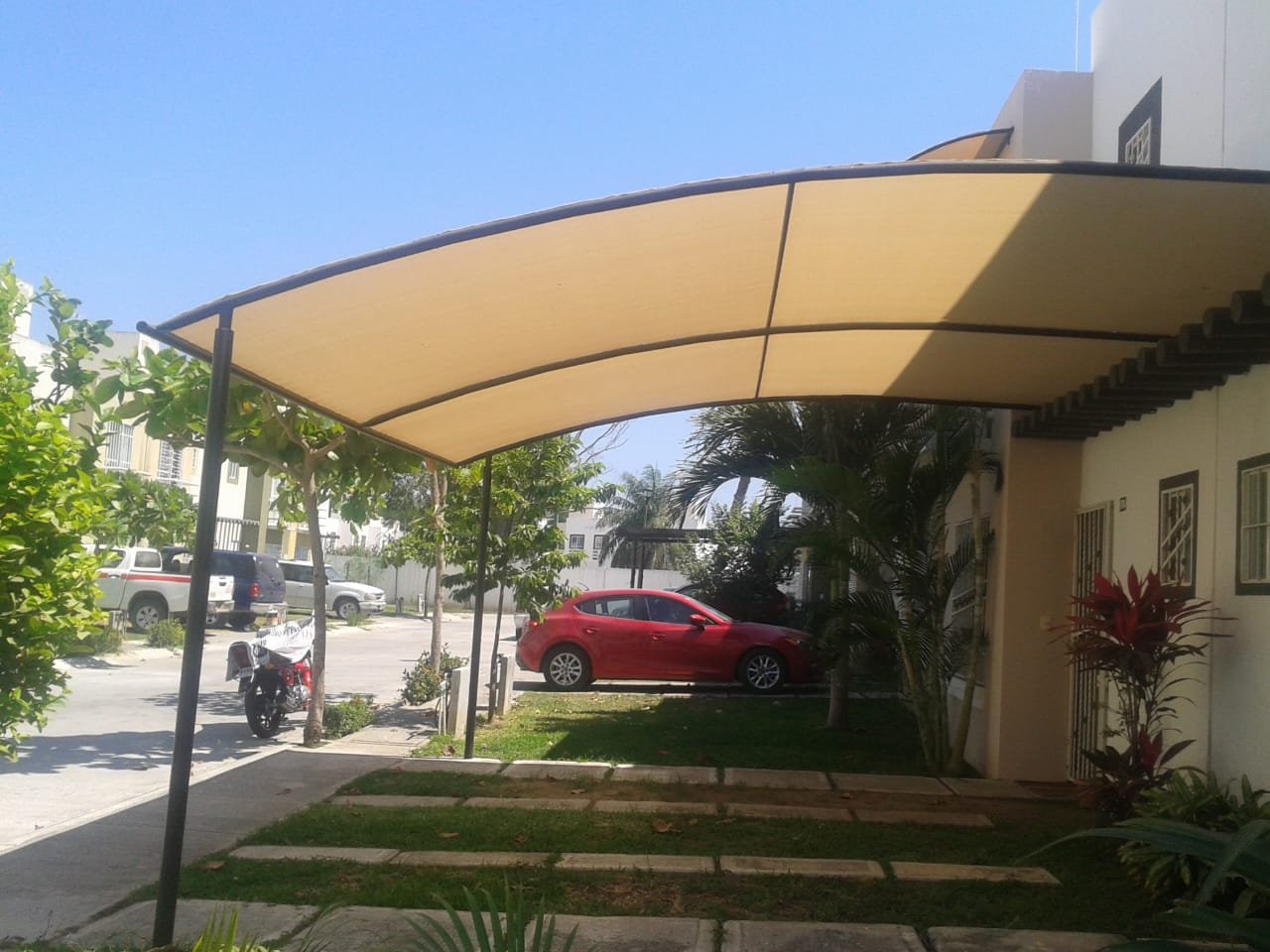 Cochera con toldo fijo semicurvo en la entrada de una casa