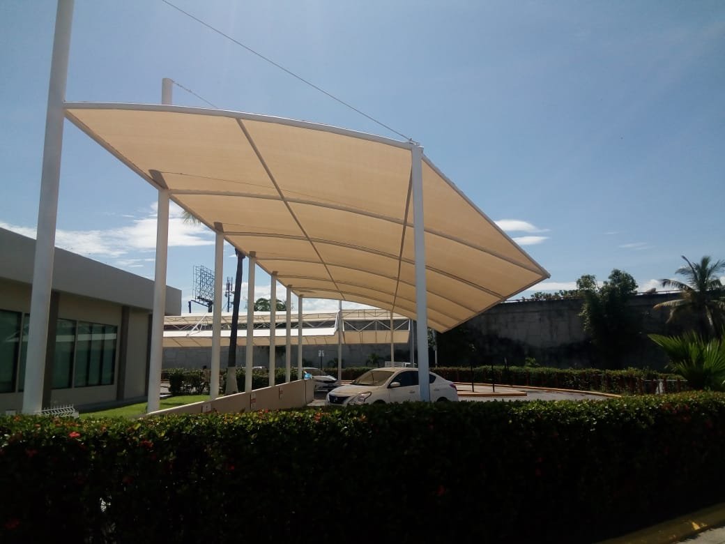 Toldo fijo semicurvo cubriendo el estacionamiento de un edificio de oficinas