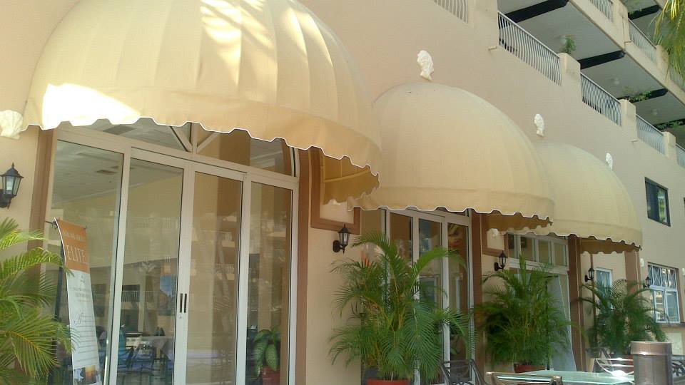 Toldos fijos de media naranja sobre las ventanas de un local comercial