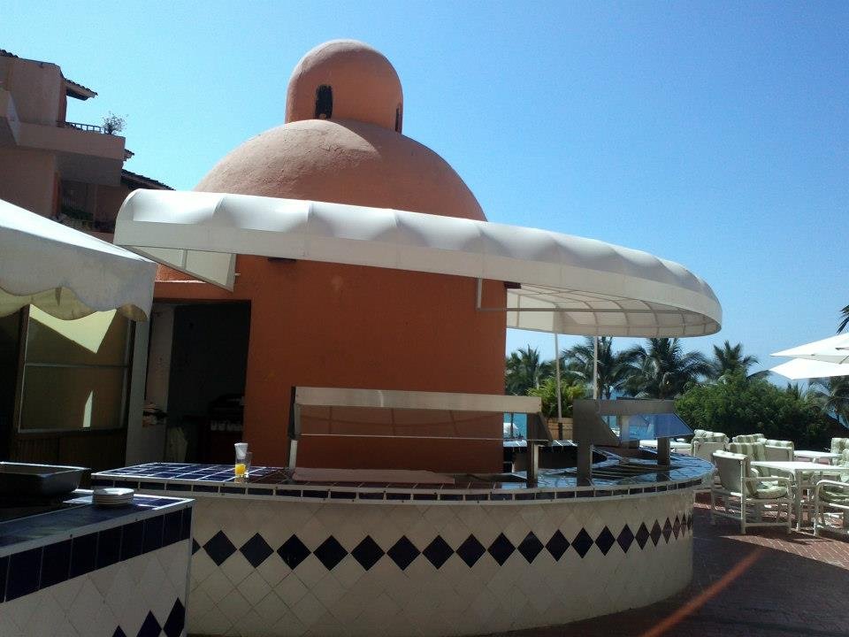 Toldo fijo cubriendo la barra circular de un bar al aire libre