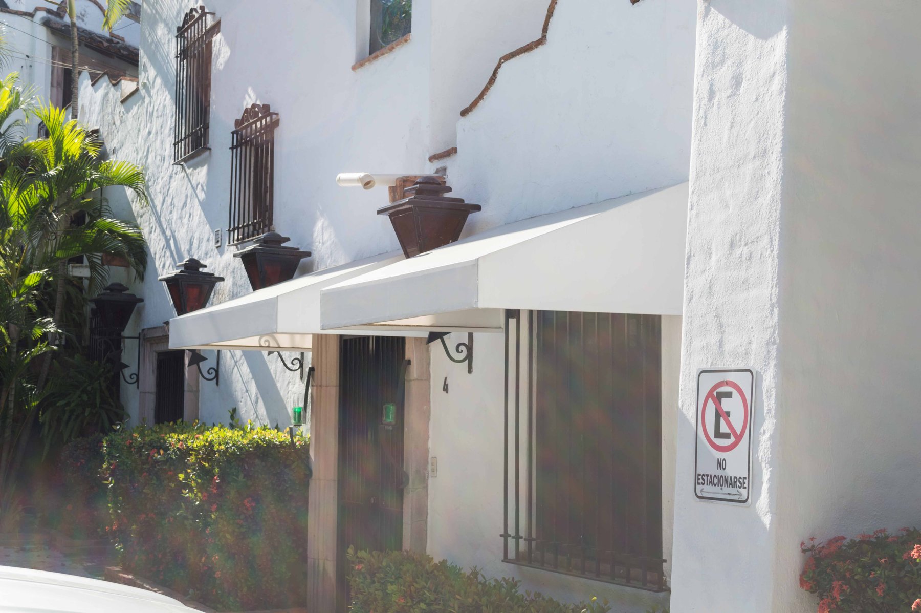 Toldo fijo de un agua instalado sobre la entrada de una fachada blanca
