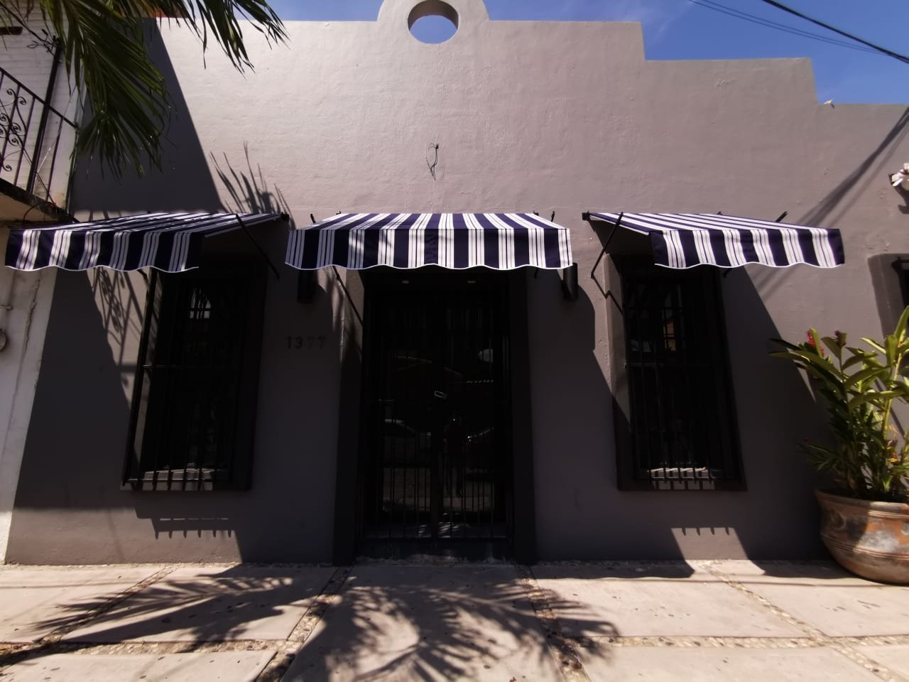 Toldos fijos de un agua a rayas blanco y negro sobre las ventanas de una fachada